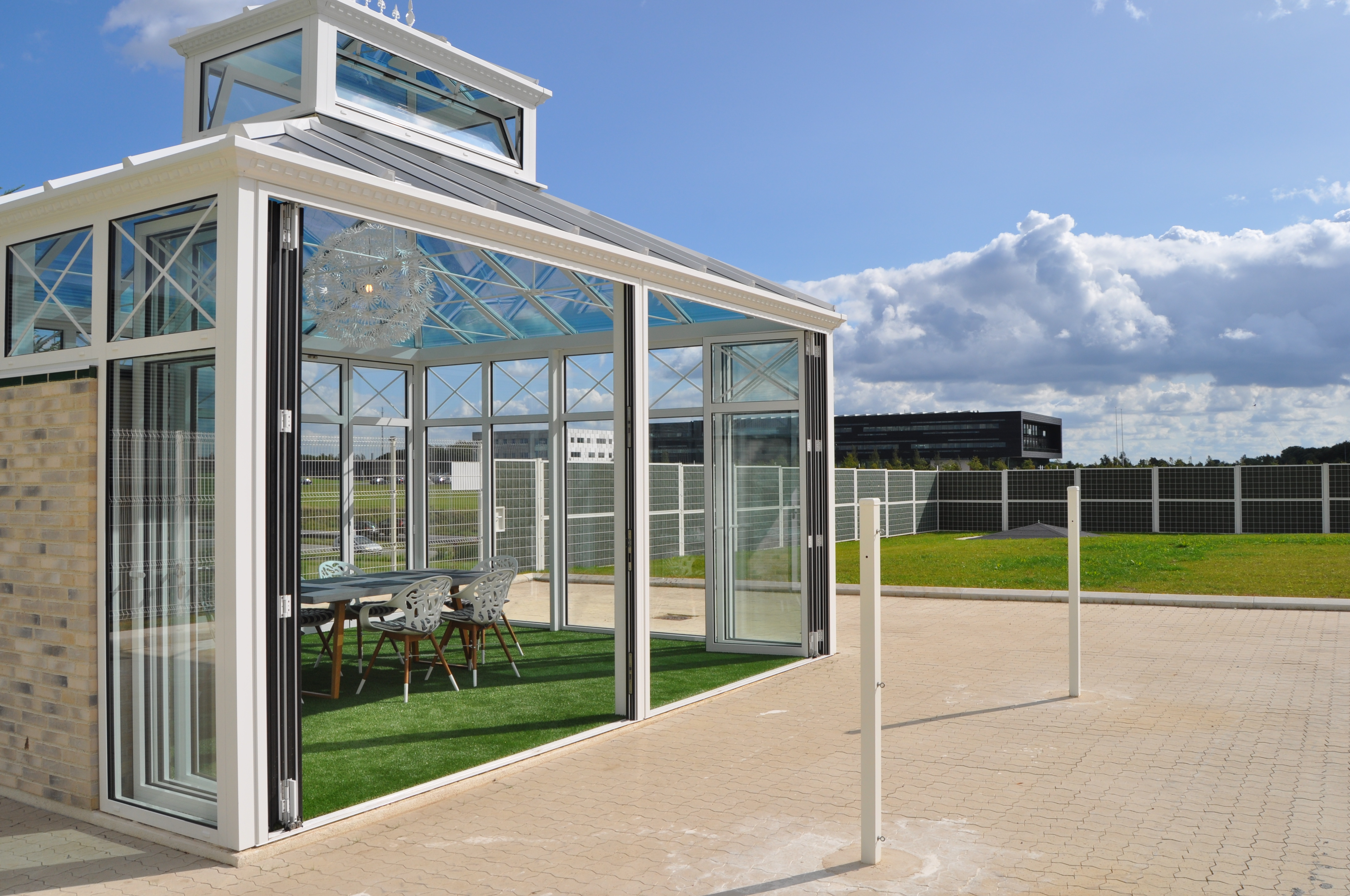 Pavillon med store panoramavinduer på en virksomheds fællesareal afskærmet med Noistop® Steel støjhegn fra Poda Hegn