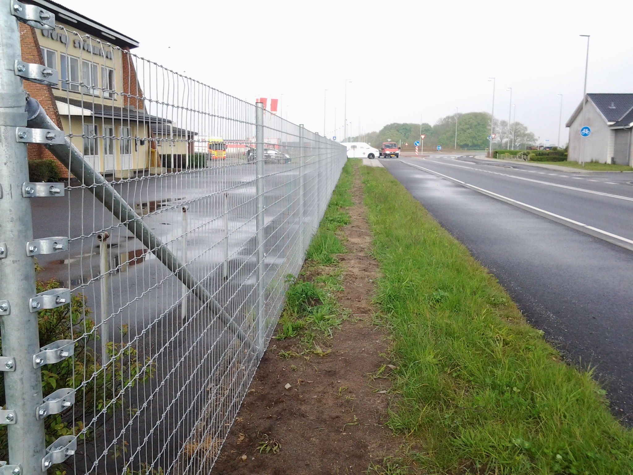 Ud til en vej er der sat et højt Multinet hegn op for at beskytte en virksomhed