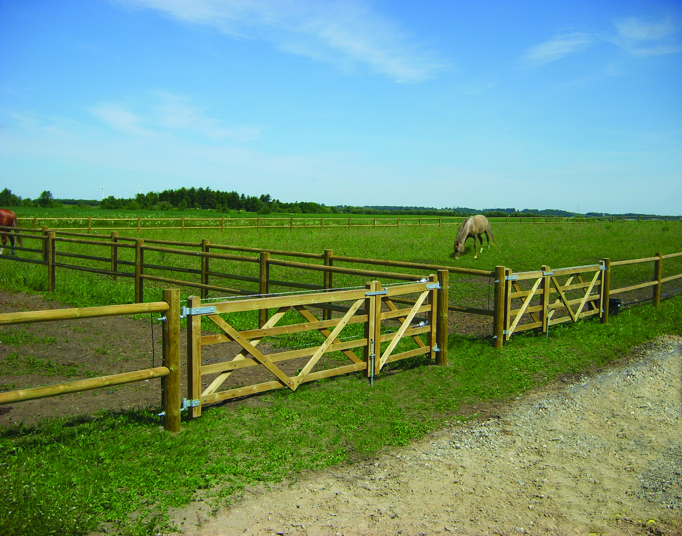 En hest står i den indhegning, som er længst væk. Den indhegning der er tættest på er tom. Begge indhegninger er afsluttet med en Country Farmer låge.