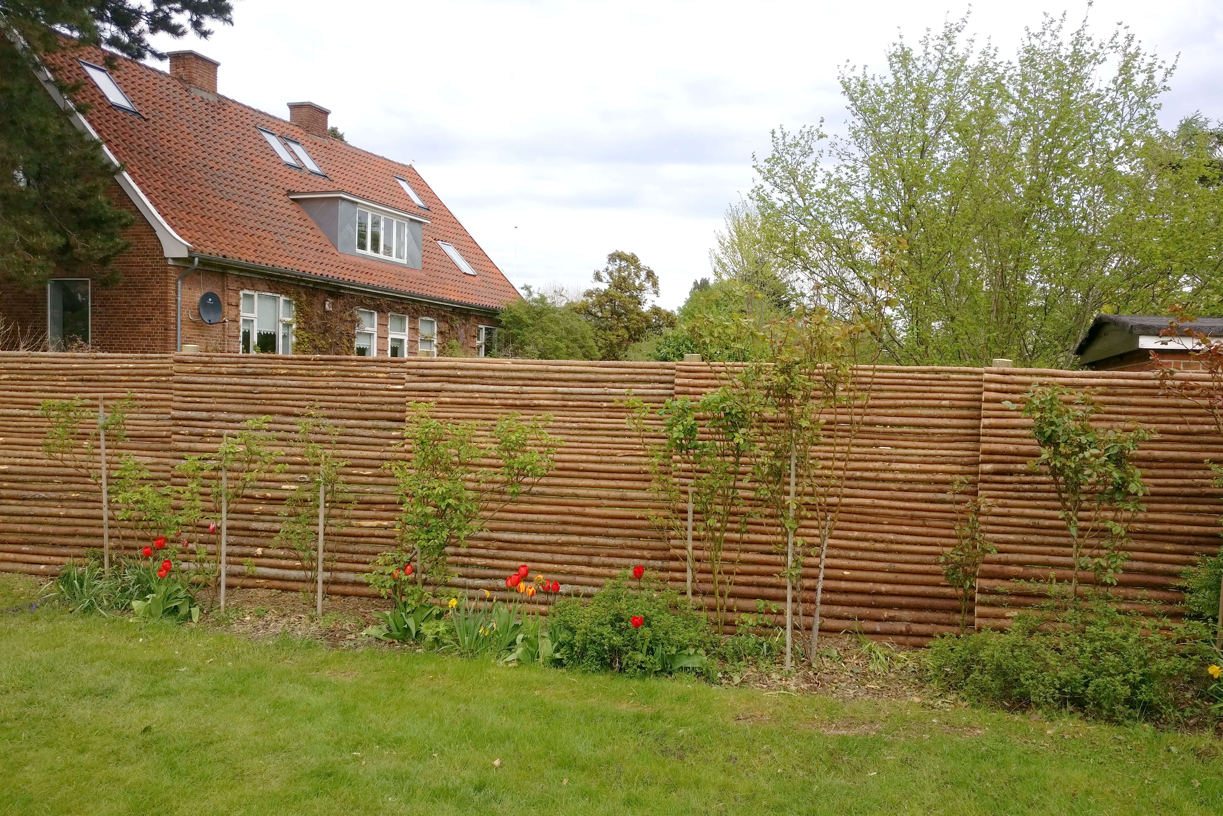 Havehegn lavet i gramrafter med bark bruges som barriere imellem to haver