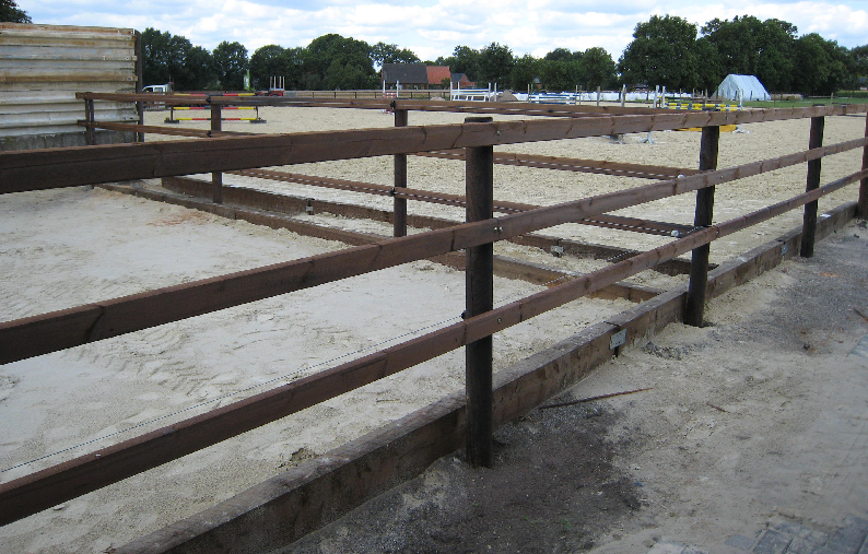 Paddock med tre lægter. I baggrunden ses en springbane.