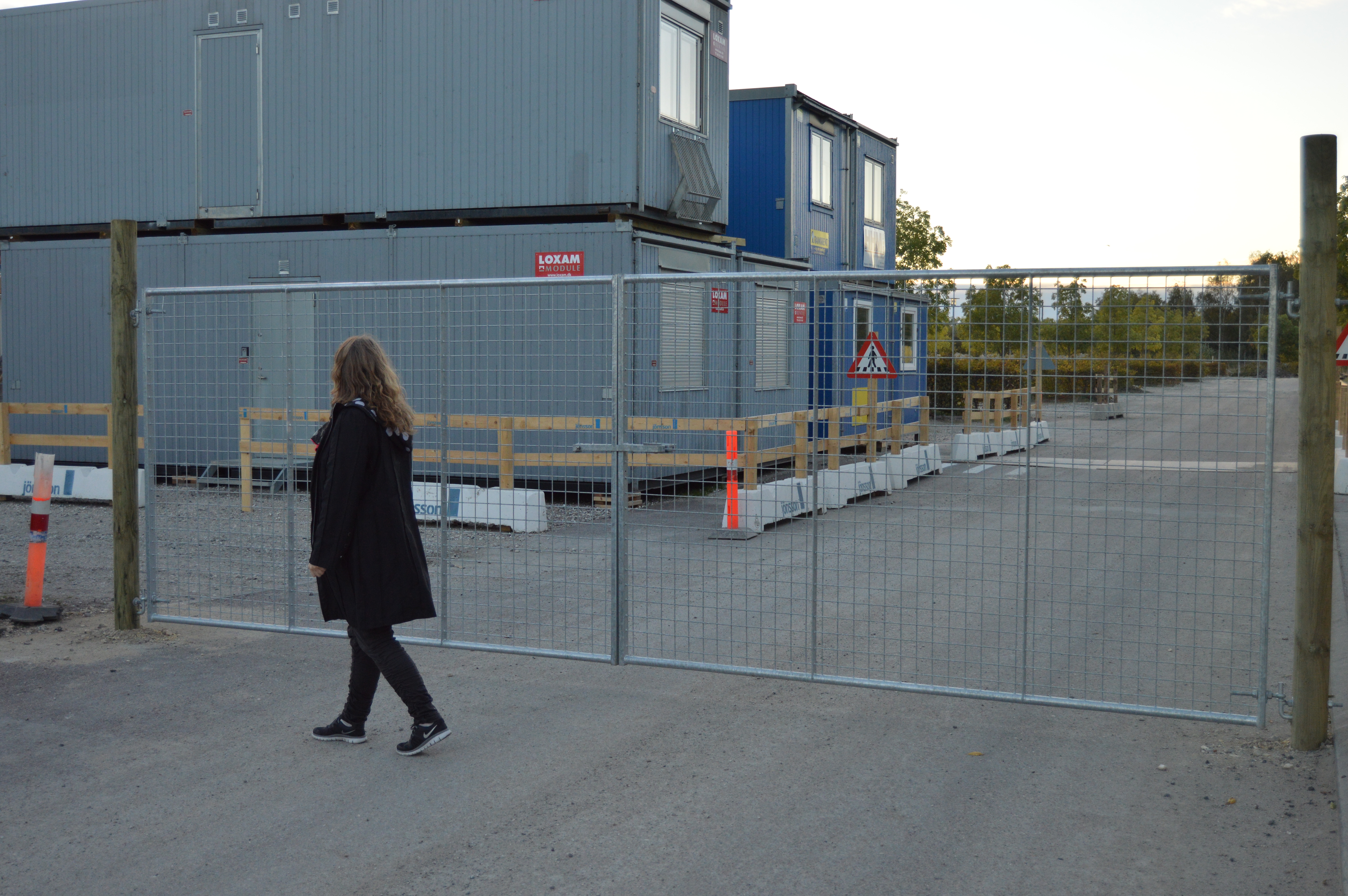 En dame går foran en letvægtslåge, der er monteret ved en byggeplads