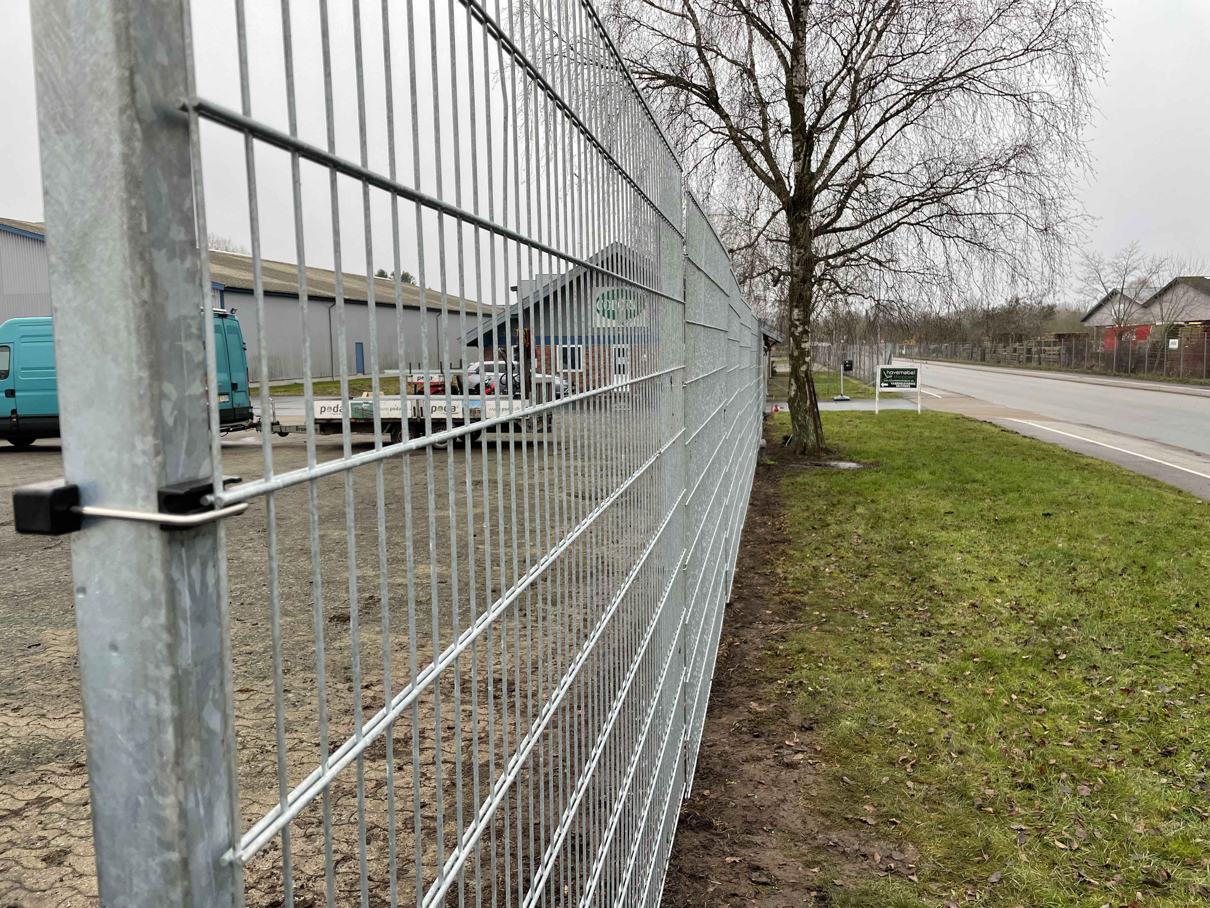 I et industri område er der monteret et gråt panelhegn for at beskytte en virksomhed