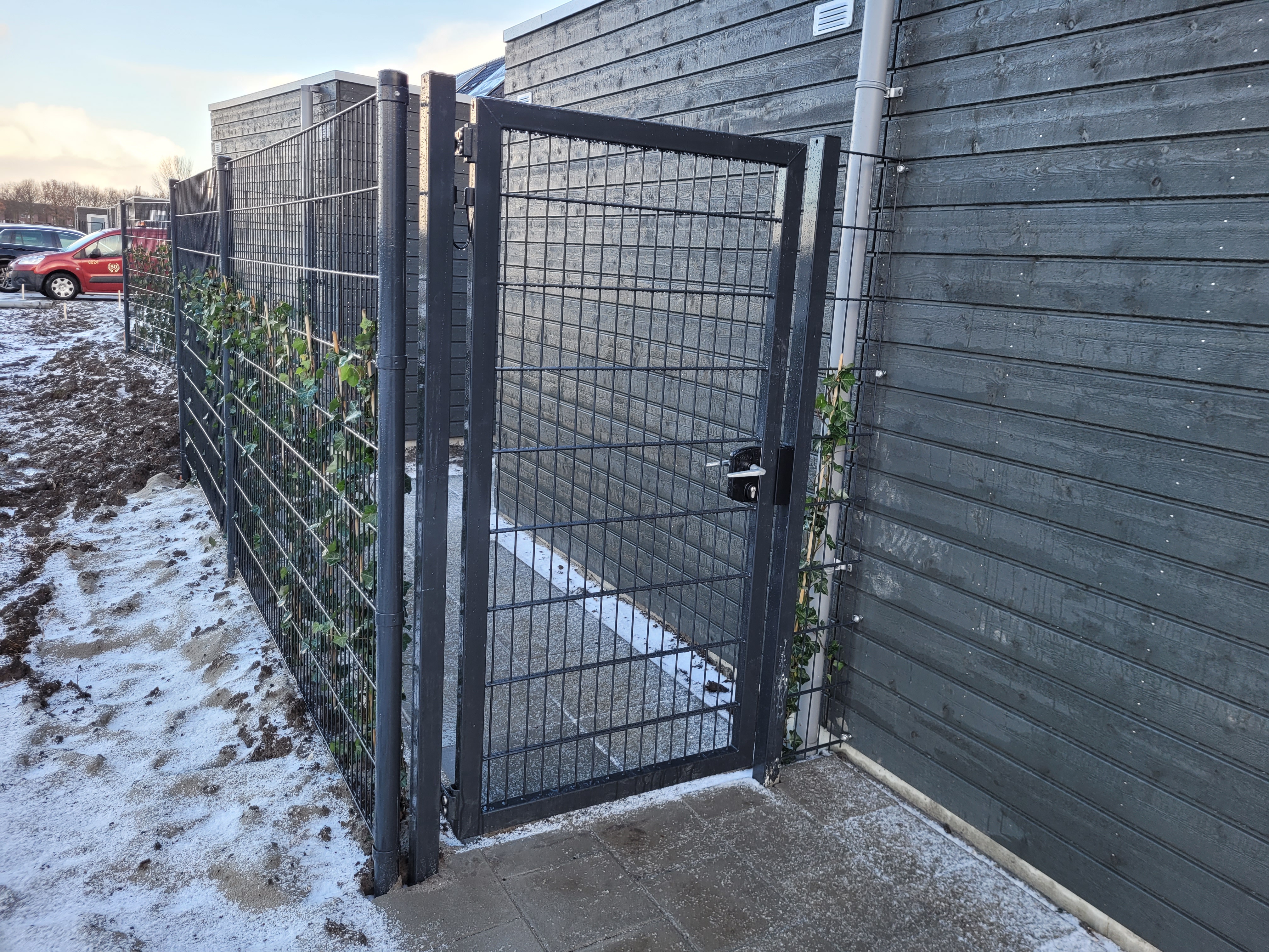 Bag på et skur er der blevet monteret en låge efterfulgt af et panelhegn