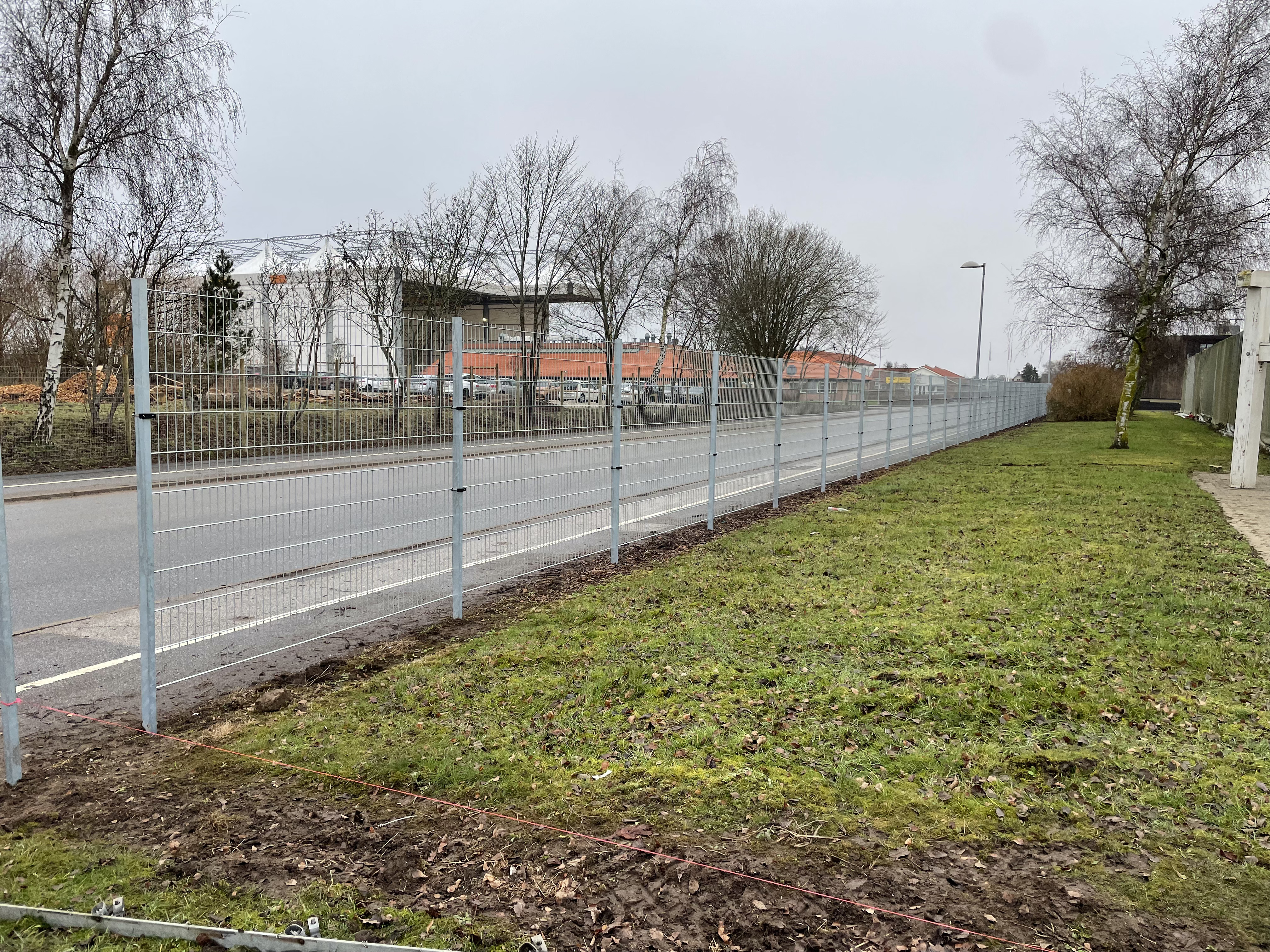 En virksomhed har fået opsat et gråt panelhegn ud mod en vej, så de er beskyttet mod tyveri og hærværk