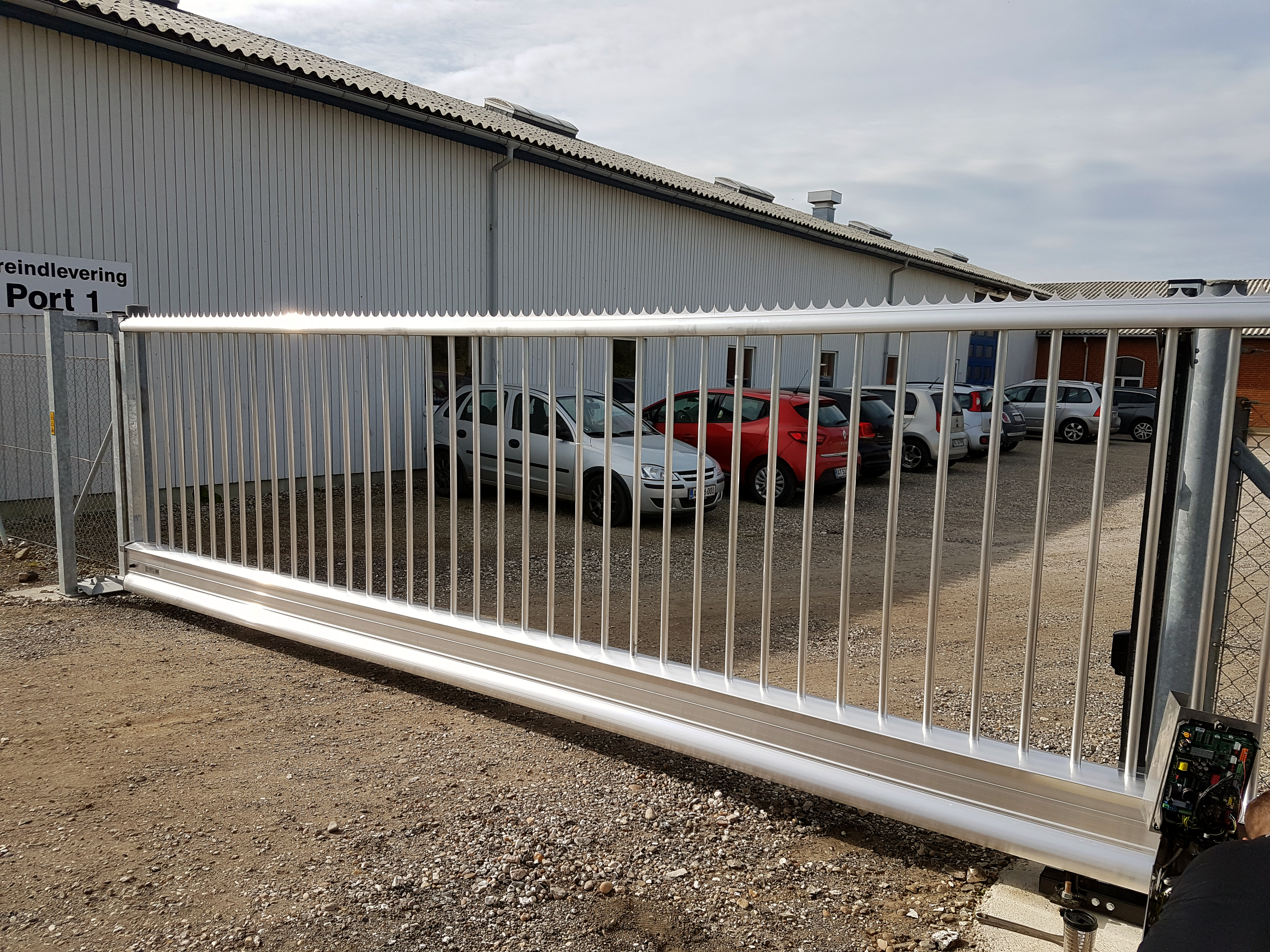 I forgrunden er en grå svæveport, bagved holder der 6 biler parkeret