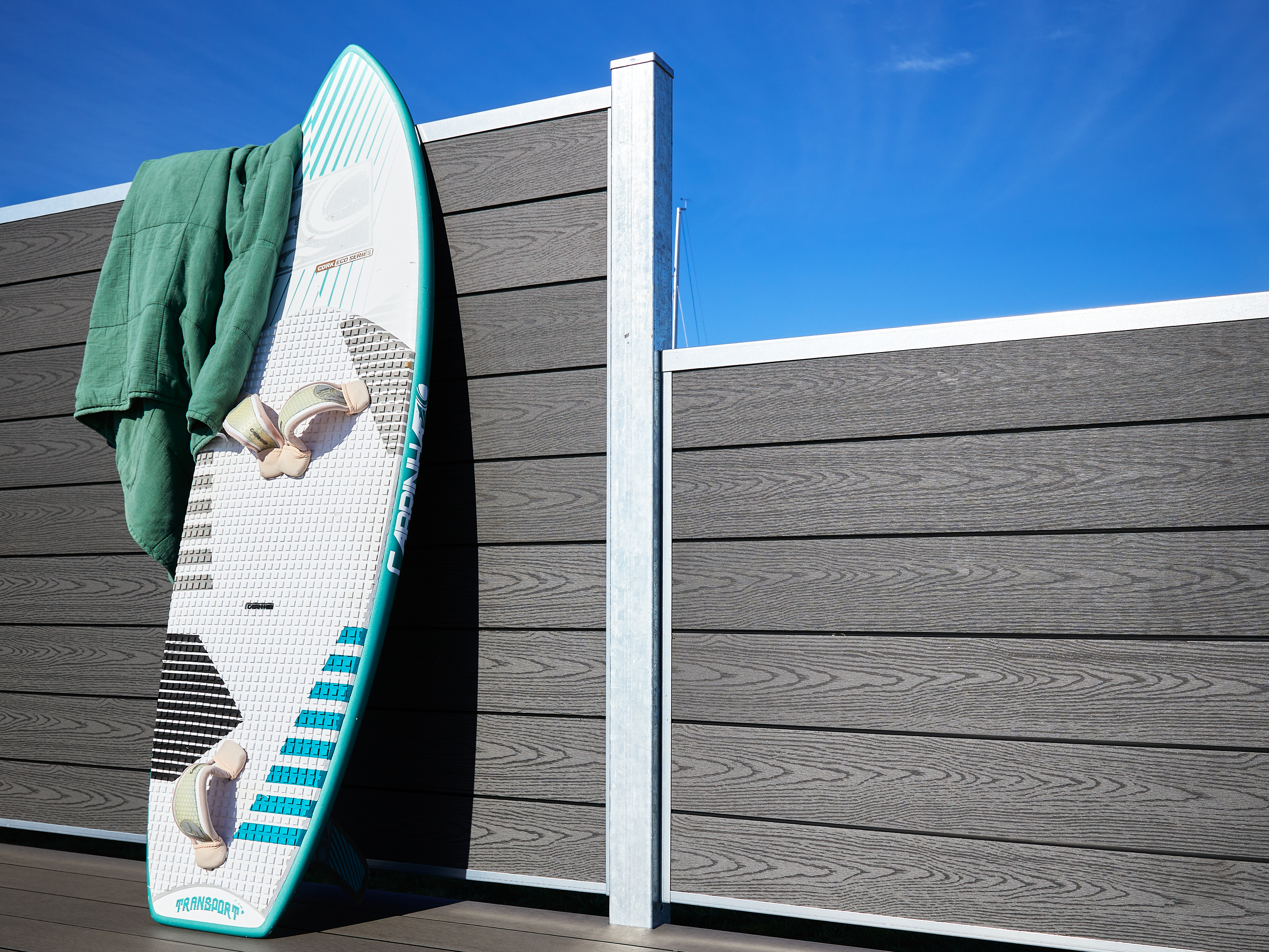 Koksgrå komposithegn fra Poda i to forskellige højder med surfboard