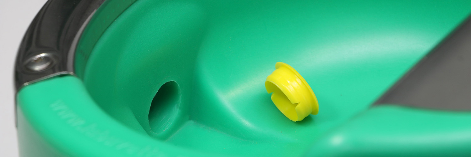 Nærbillede af en grøn drikkekop med en gul plastprop ved en åbning