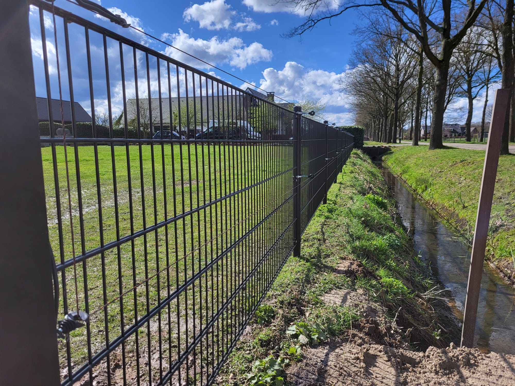 På et panelhegn ud til en å, er der monteret to strømførende tråde for at øge sikkerheden